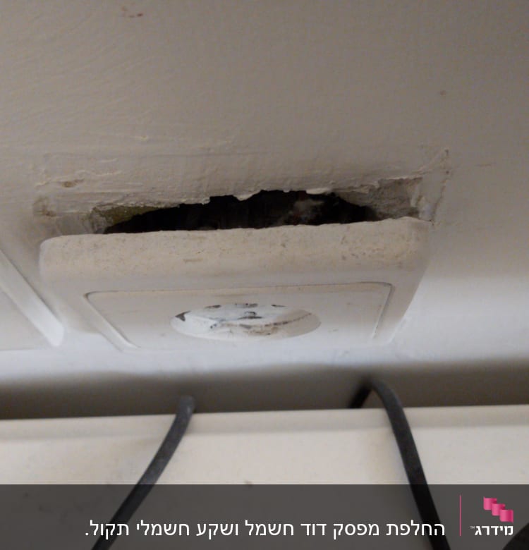 שקע חשמל בקיר עם חוטי חשמל חשופים